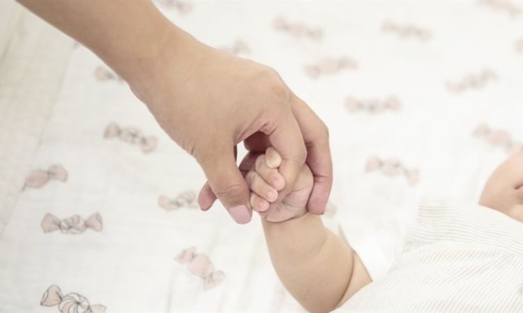 Recién nacido sostiene la mano de su madre