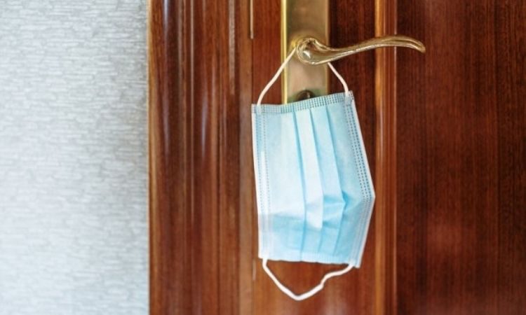 Mascarilla colgada en la manija de una puerta